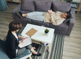 Jak wygląda współpraca hipoterapeuty z lekarzem i fizjoterapeutą przy planowaniu terapii Terapeuta rozmawia z pacjentem na kanapie w gabinecie
